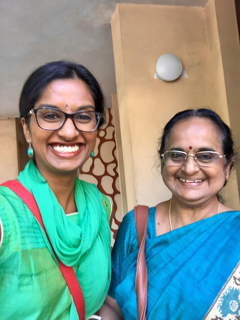 Two women in green and blue saris smiling together for a selfie