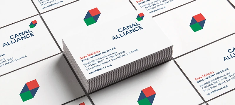 Stack of Canal Alliance business cards for Sara Matson, Development Director, with a red and green cube logo