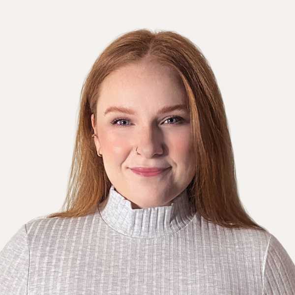 Professional headshot of Erica Kroening, Project Manager at Mission Minded, a woman with long red hair wearing a light gray ribbed turtleneck sweater, smiling softly against a plain background.